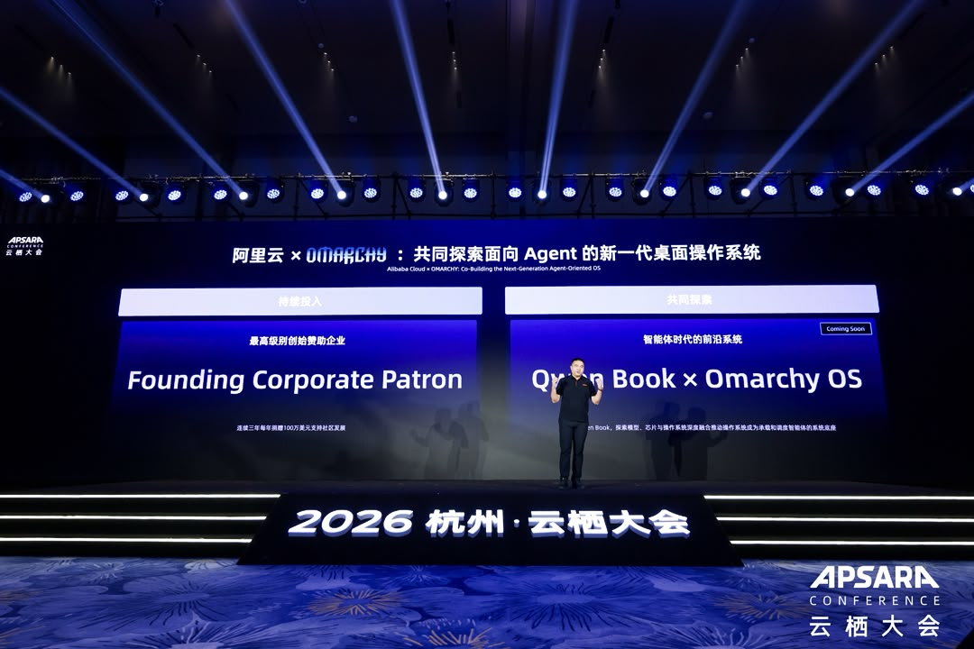 Hangzhou में 2026 Apsara Conference में स्टेज पर Alibaba Cloud द्वारा अपनी Founding Corporate Patron प्रतिबद्धता और Omarchy के साथ Qwen Book सहयोग की घोषणा।